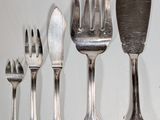 several forks and spoons are lined up on a white surface