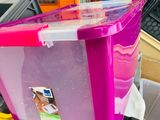 a pink box with a lid sitting on top of a pile of other boxes