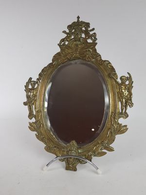 un miroir ancien avec un cadre doré posé sur un support blanc