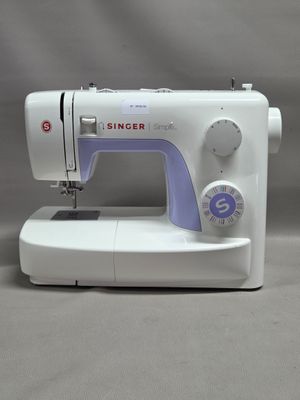 La machine à coudre est posée sur la table, prête à l'emploi.