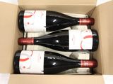 three bottles of red wine in a cardboard box on a table