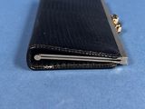 black leather wallet with a gold clasp on a blue surface