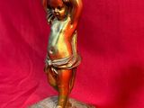 statue en bronze représentant un garçon tenant une bouteille, posée sur un socle