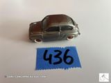 une petite voiture en argent posée sur une feuille de papier bleue