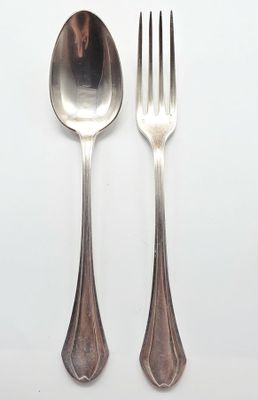 deux cuillères et une fourchette en argent sur une surface blanche