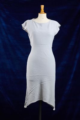 une robe blanche posée sur un mannequin, devant un fond bleu
