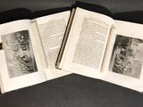 three open books on a table with a black and white photo of a group of people in the background