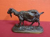 statue of a goat on a wooden base on a red surface