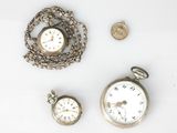 three different types of watches and a coin on a white surface