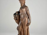 an antique wooden statue of a woman holding a vase