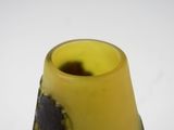 a yellow vase with a black flower on it