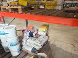 de nombreux seaux de peinture posés sur une étagère dans un entrepôt
