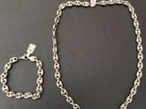un gros plan d'un collier et d'un bracelet à chaîne en argent posés sur une table