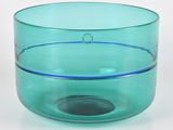 un bol en verre vert à bord bleu posé sur une surface blanche