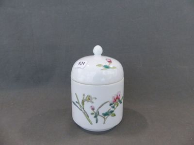 un petit pot blanc orné de fleurs, posé sur une table