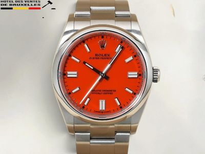 une photo d'une montre au cadran orange, montée sur un bracelet argenté