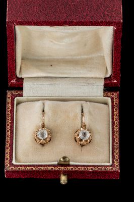 une image représentant une paire de boucles d'oreilles dans un écrin, sur fond noir