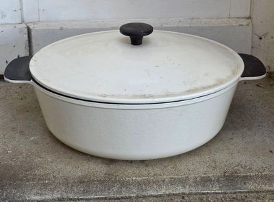 une cocotte blanche avec une poignée noire posée par terre