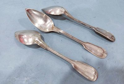 three silver spoons sitting on top of a table next to each other