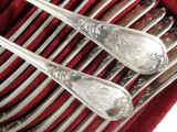 two silver spoons sitting on top of a stack of red napkins