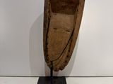 an old wooden boat on a black stand against a white wall
