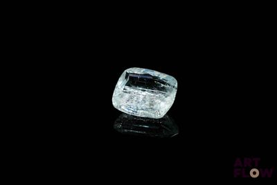 un gros plan d'un diamant posé sur une surface noire, sur fond noir