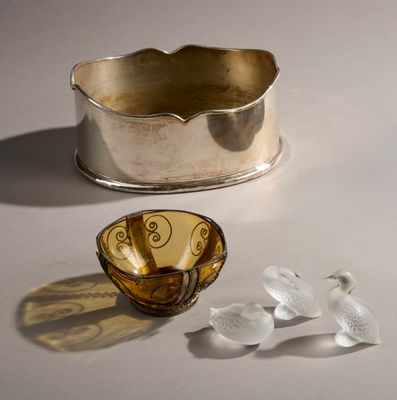 un bol en argent et un vase de fleurs posés sur une table