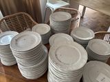 many plates stacked on a table with a chair in the background