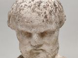 an old statue of a man ' s head is shown against a gray background