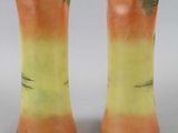 pair of orange and green vases sitting on top of a white table