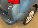 the rear end of a blue van with a flat tire