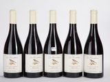 quatre bouteilles de vin sont alignées sur une surface blanche