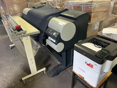 une grande imprimante placée à côté d'une machine d'impression dans un entrepôt