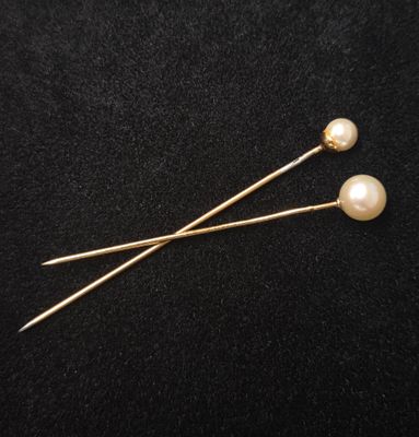 une paire d'épingles en perles et en or sur fond noir