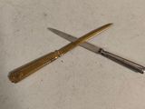 a knife and a pen on a table next to each other