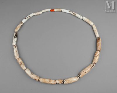 un collier composé de perles en os, avec une perle rouge et blanche