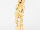 une figurine en ivoire sculptée représentant un garçon assis sur un rocher