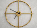 une horloge dorée aux aiguilles noires accrochée à un mur blanc
