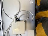 une personne debout à côté d'une table sur laquelle se trouvent un ordinateur portable et un chargeur