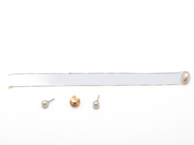 une photo représentant une paire de boucles d'oreilles et un collier posés sur un fond blanc