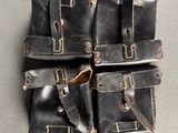 four black leather pouchs on a gray surface with one open