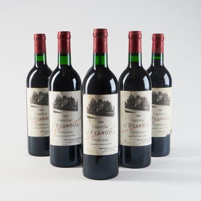 quatre bouteilles de vin rouge sont alignées sur une surface blanche