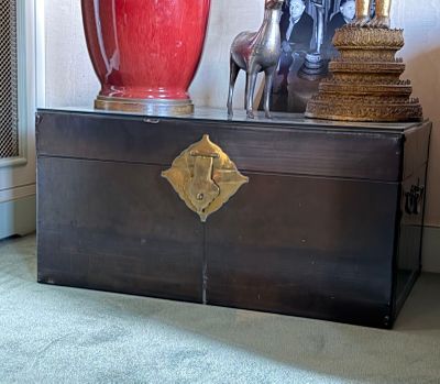 a large red vase sitting on top of a wooden chest