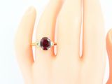 a woman ' s hand holding a ring with a garnett on it
