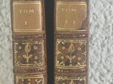 pair of antique leather bound books sitting on top of a white surface
