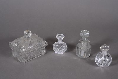three clear glass bottles and a small glass box on a gray surface
