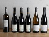 six bottles of wine are lined up on a wooden table