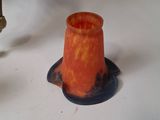 a small orange vase sitting next to a gold candle holder