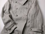 une photo d'un manteau gris posé sur une table blanche