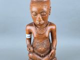 une image représentant une statue en bois d'une femme assise sur un tabouret